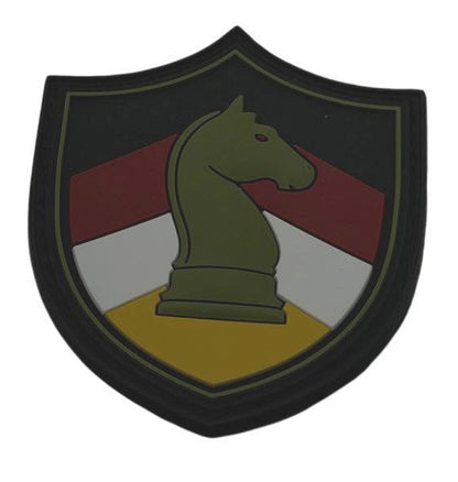 A shield-shaped military patch featuring a green chess knight on a yellow base, with red, white, and black diagonal stripes in the background.